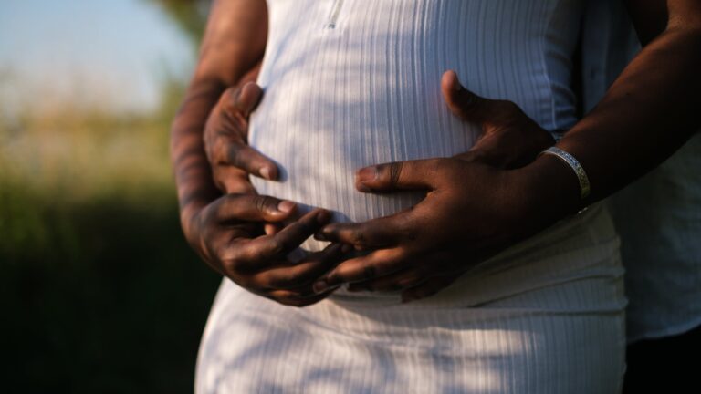 hands of a couple embracing the baby inside her growing belly