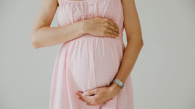 close up photo of pregnant woman wearing pink checkered dress